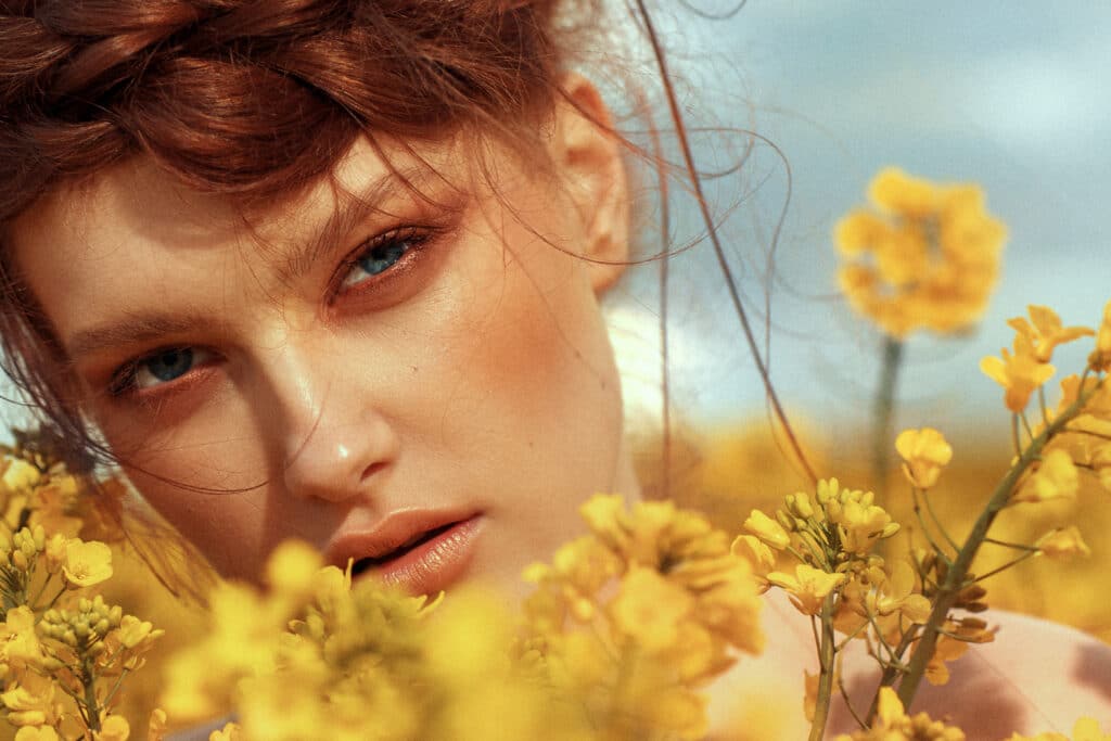 Young fashion model portrait with ginger hair and blue eyes in yellow field