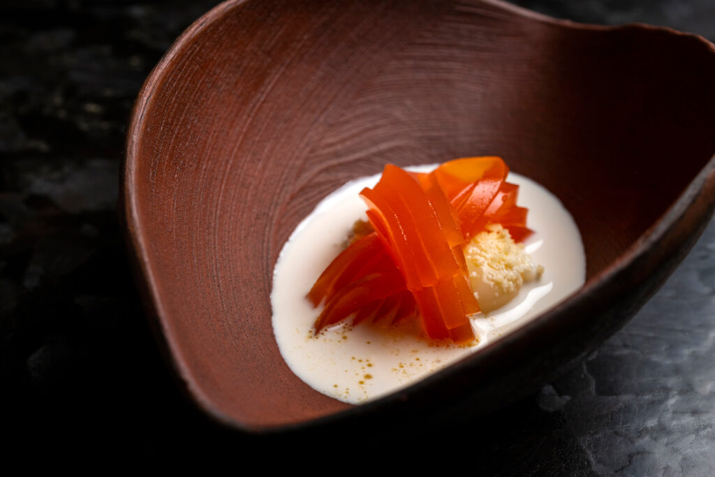 Orangen-Gelee-Dessert mit cremiger Soße in einer braunen Schüssel. Foto von Evan Sung