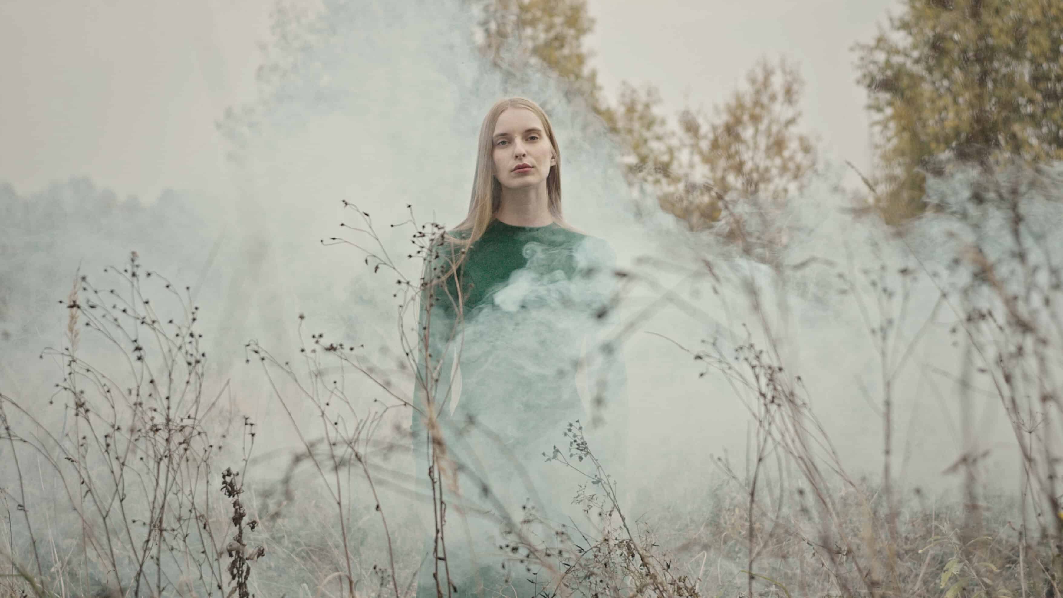 Fashion model posing in smoke and dry plants
