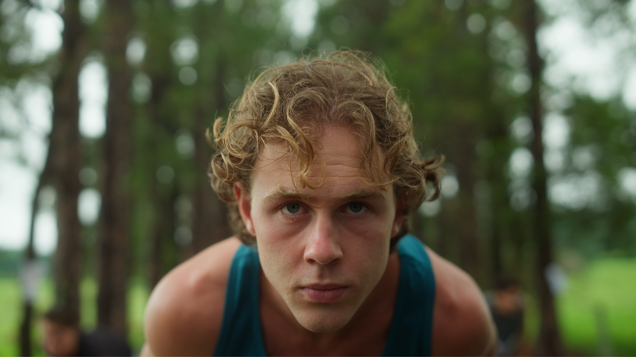 Close-up of a determined runner leaning forward in a forest