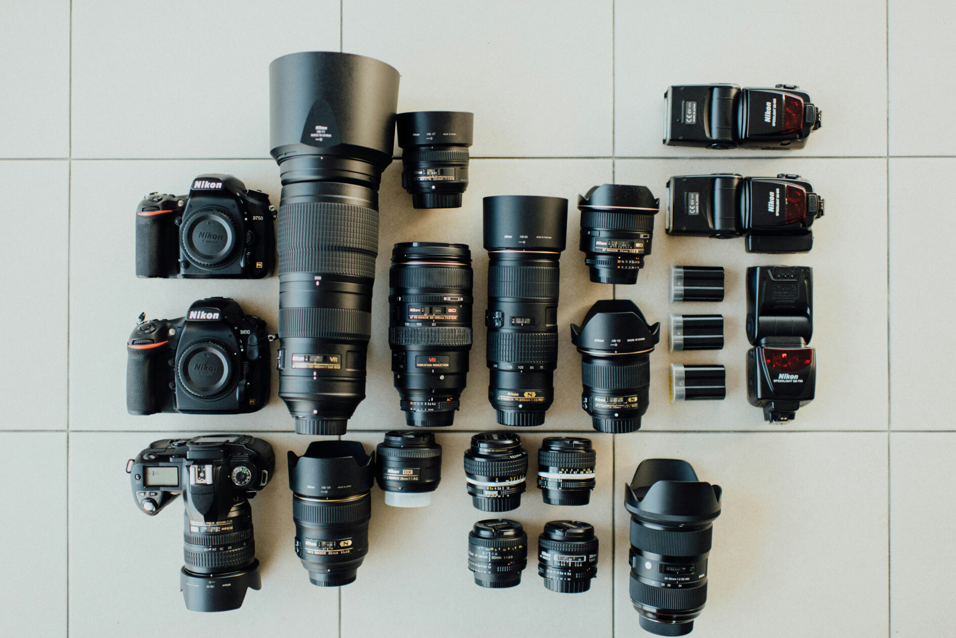 Eine flache Ebene mit professioneller Fotoausrüstung, darunter zwei Nikon-Kameragehäuse, mehrere Objektive in verschiedenen Größen sowie mehrere Blitzgeräte und Zubehör. Dieses Bild veranschaulicht die große Auswahl an Ausrüstung, die du bei Unternehmen wie Lensrentals und Adorama mieten kannst.