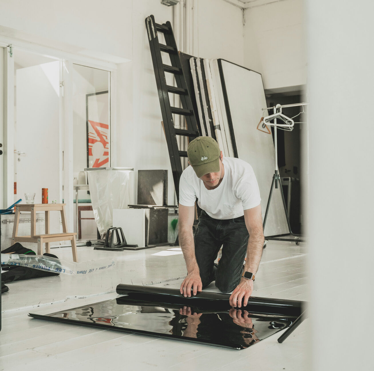 Ein männlicher Fotograf in einem weißen Studio rollt Kulissenmaterial auf