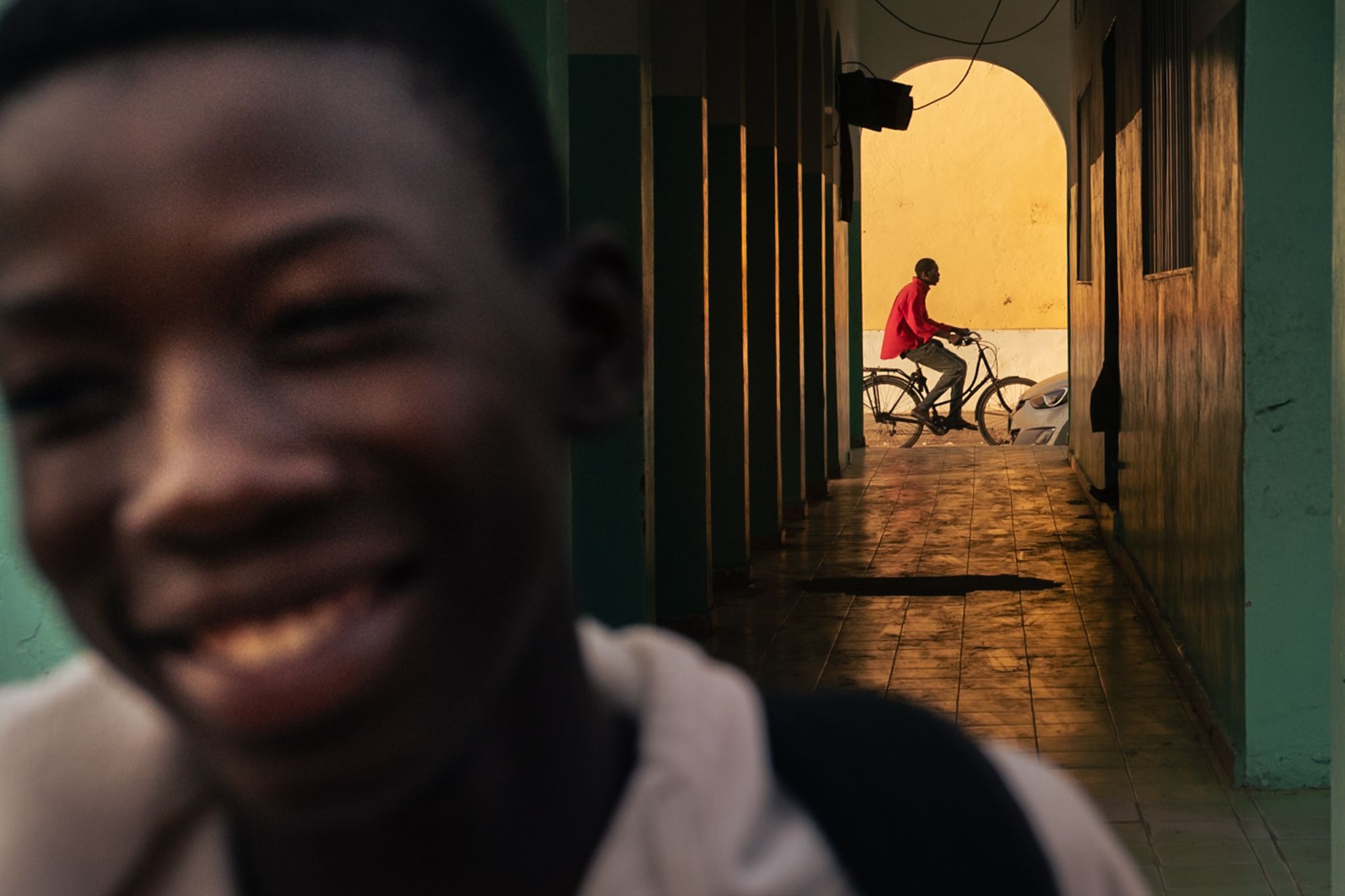 Man riding bicycle through a golden passageway with blurred child in foreground