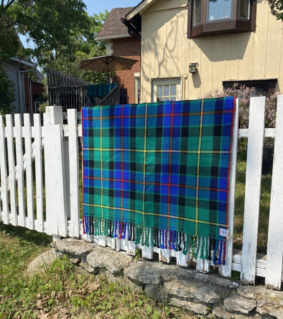 Liz Pead Tait Tartan drapé sur une clôture de piquets blancs