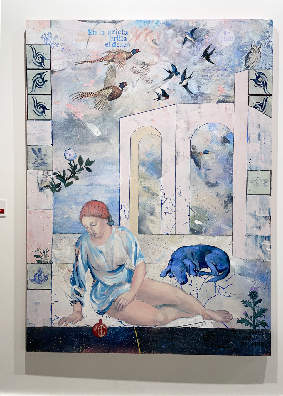 El cuadro muestra a una mujer con un vestido azul y un pañuelo rojo en la cabeza reclinada junto a un perro azul, con una granada cerca, sobre un fondo de arcos, pájaros volando y texto en español. La obra incorpora una estética de collage con elementos de realismo y surrealismo. Pintura de Los Bravu