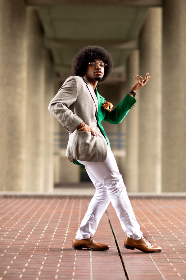 Fotografia de Remi McQuen de um homem posando com calça branca e blazer de dois tons