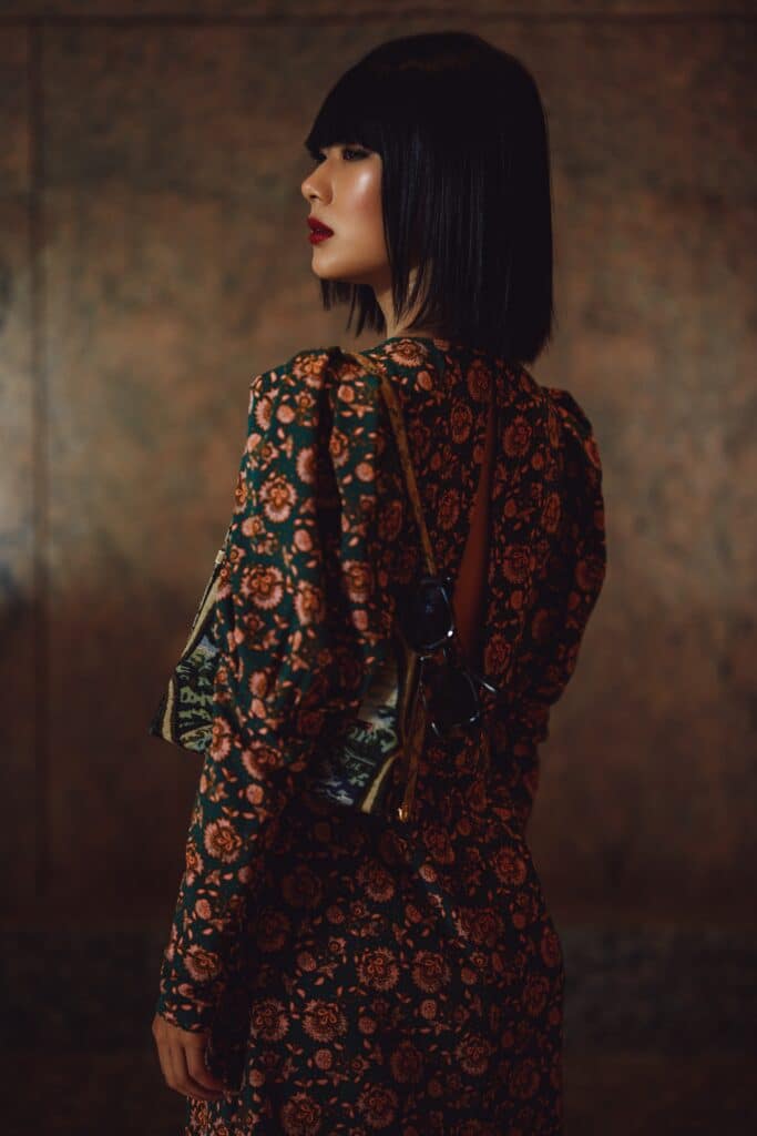 Woman with sleek bob hairstyle wearing floral patterned jacket and skirt