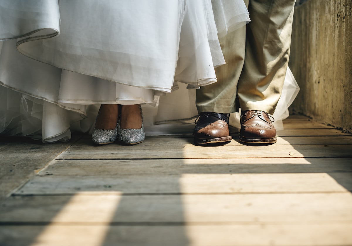 bride-and-groom-feet-standing-on-wooden-floor-PYL3EUW