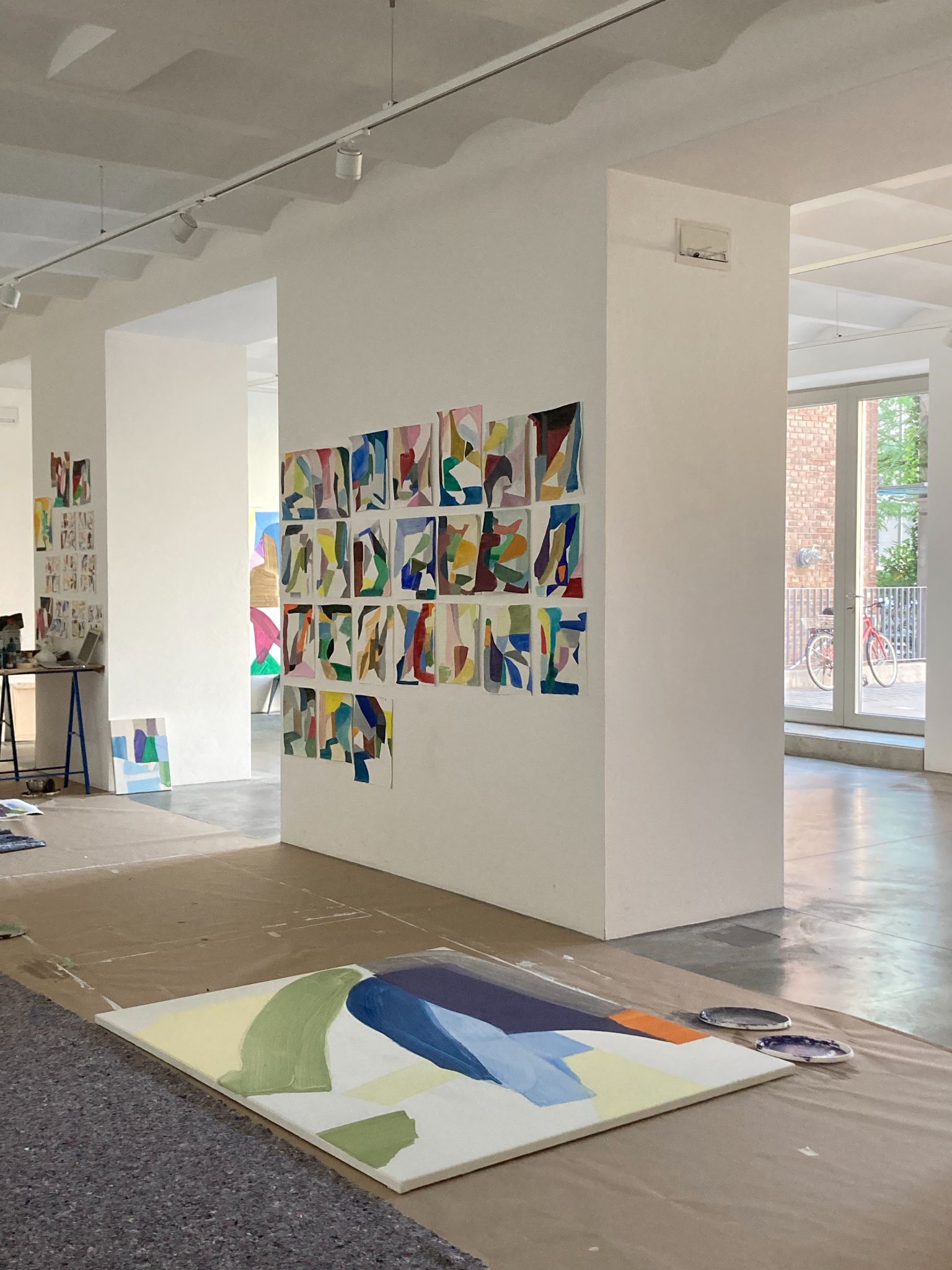 Abstract paintings displayed in a bright art studio with a large canvas on the floor.