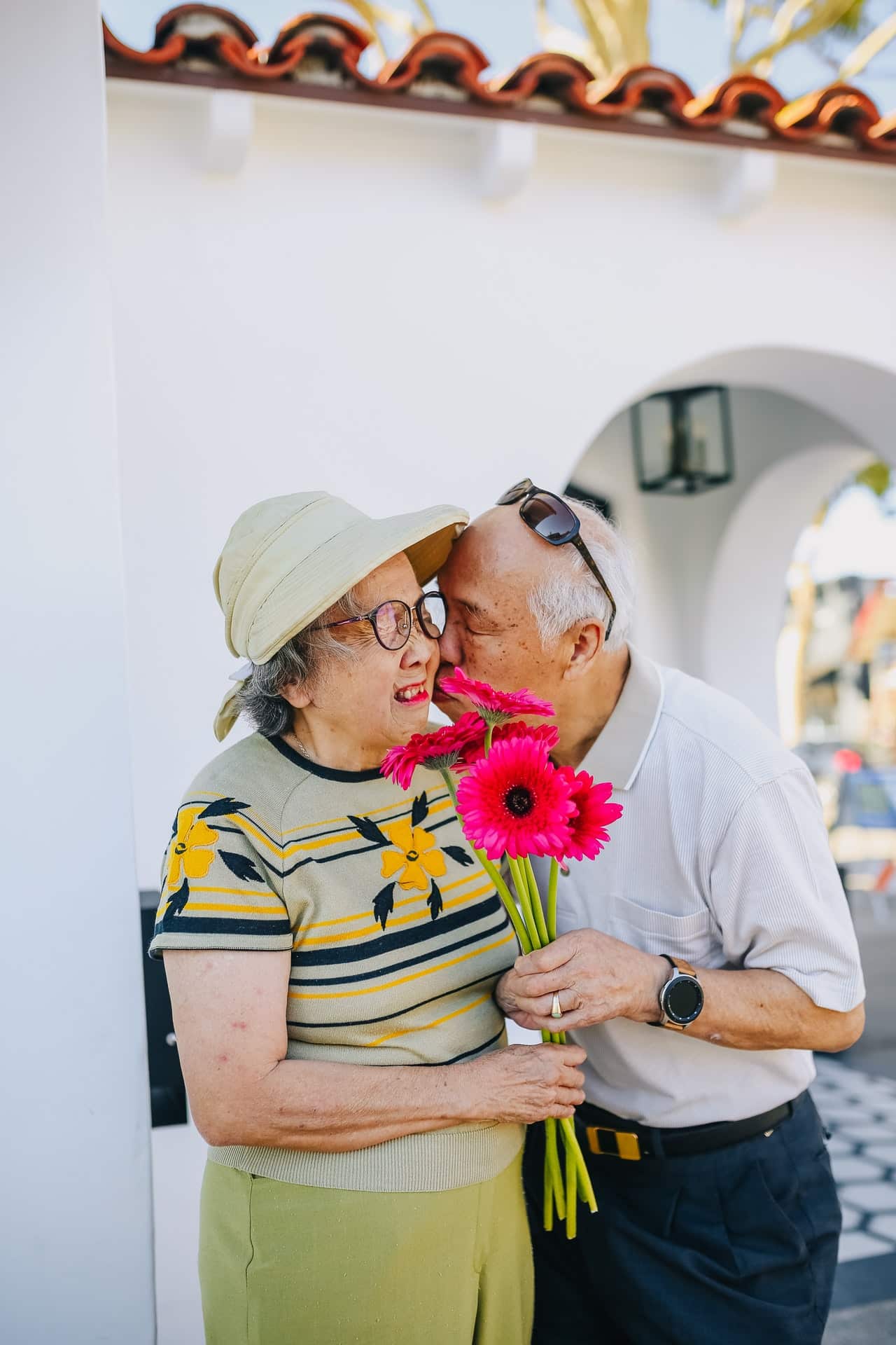 elderly couple holding red flowers