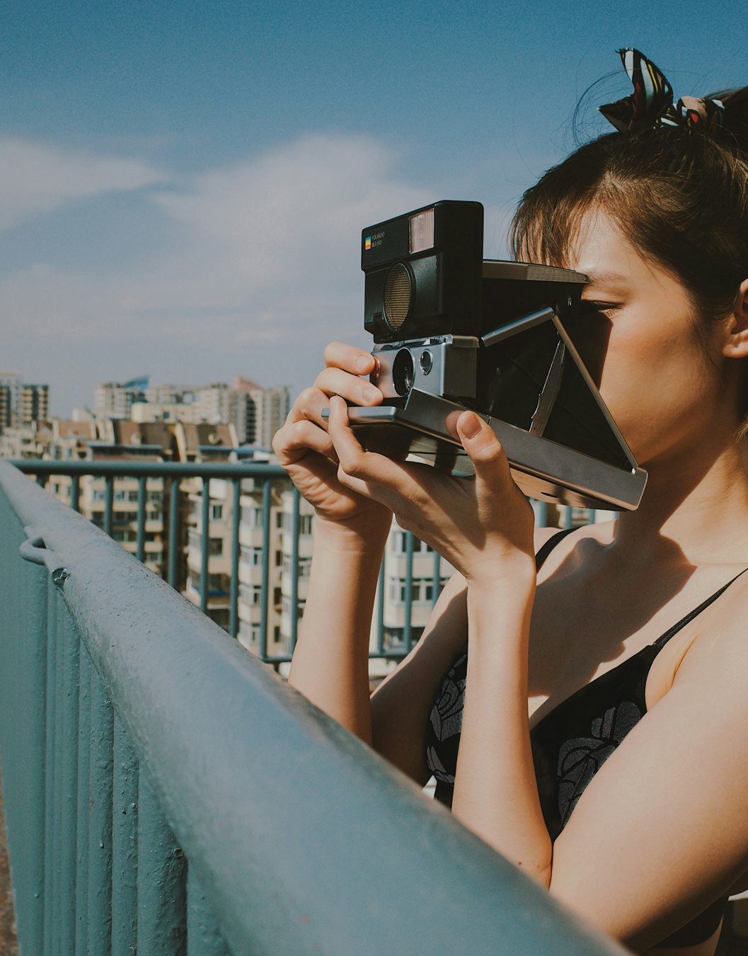 female photographer using antique polaroid to photograph a cityscape