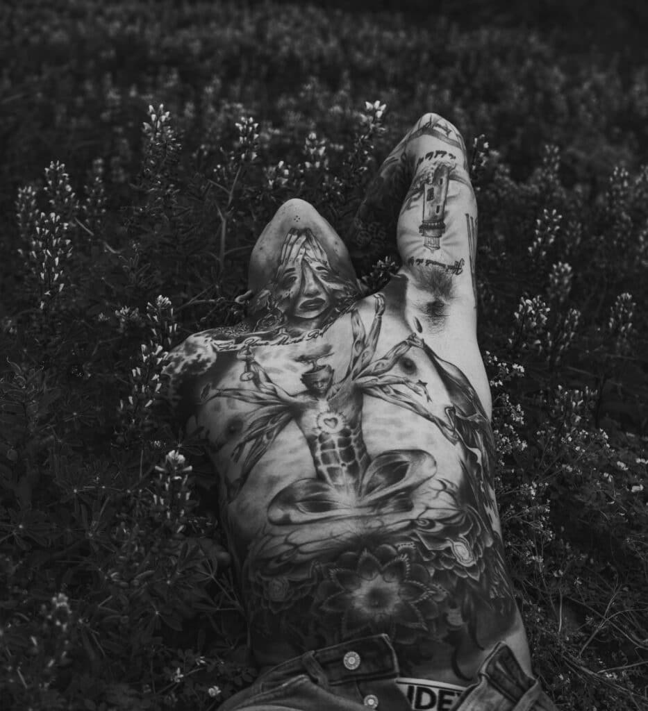 tatuajes completos de pecho y cuello en hombre tumbado en el campo