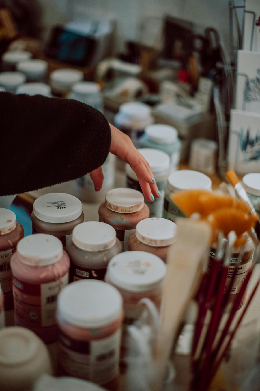 hand reaching to select a jar of paint