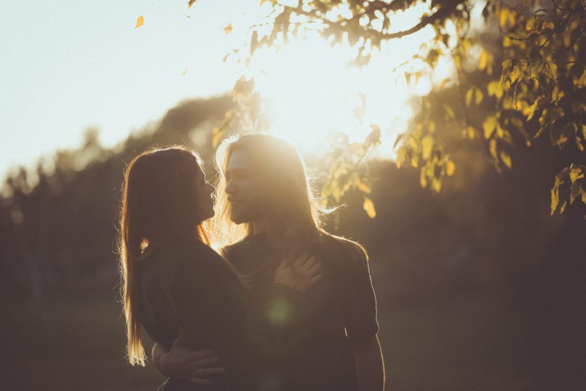 man with long hair holding a woman under the sun