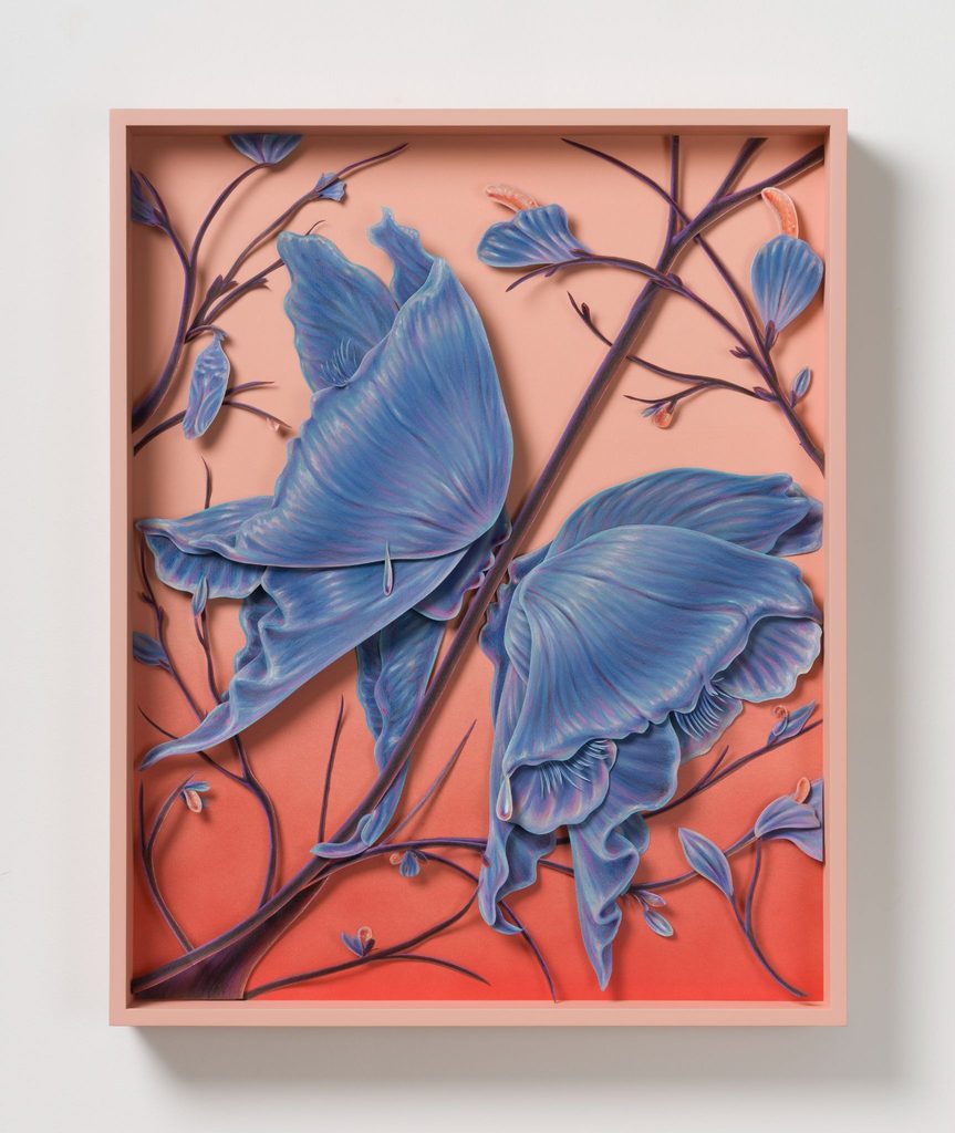 A three-dimensional paper sculpture in a pink frame features two large, textured blue flowers resembling butterfly wings, set against a gradient background of peach to red with delicate purple branches.