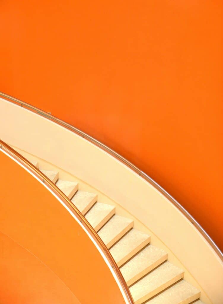 escalera marfil rodeada de paredes naranja intenso