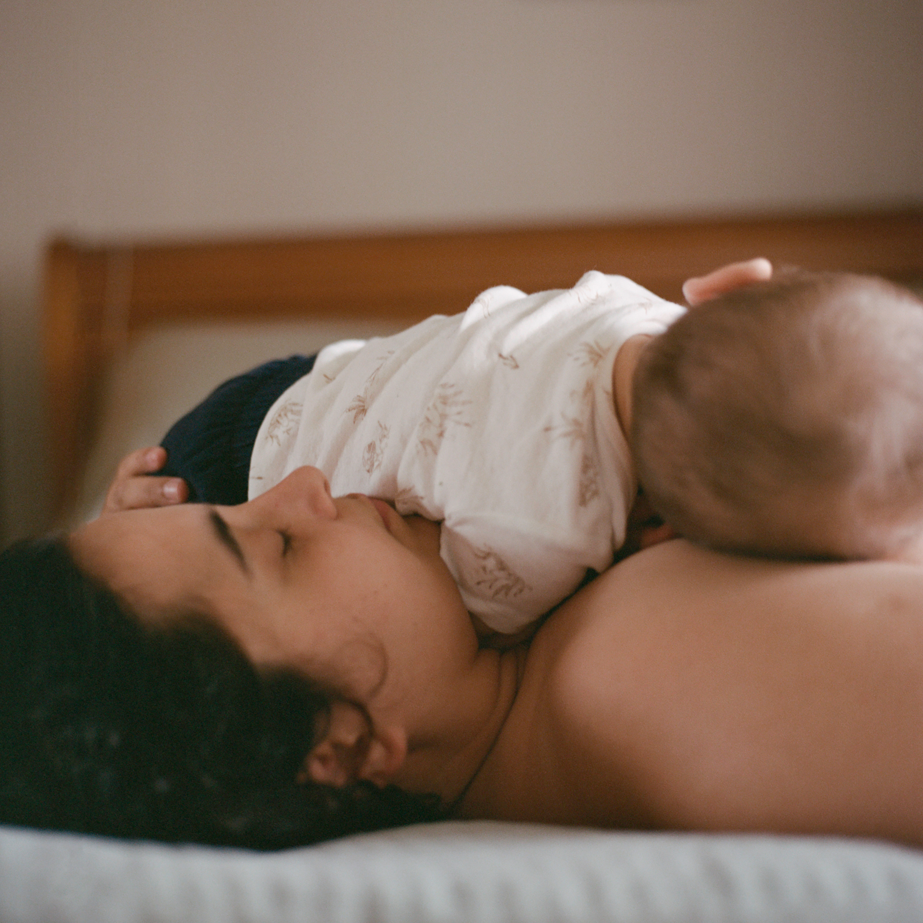 Mother holding baby close in a warm, intimate bedroom moment