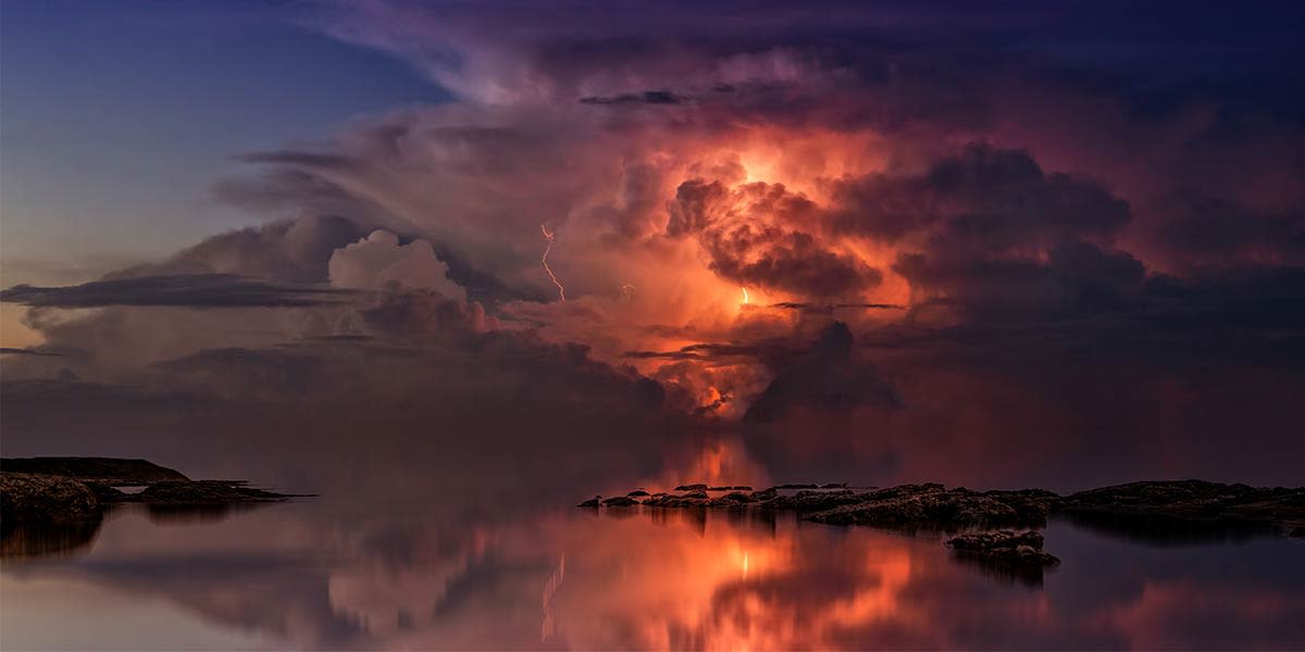 long-exposure-of-a-lightning-strike-with-a-reliection-over-water