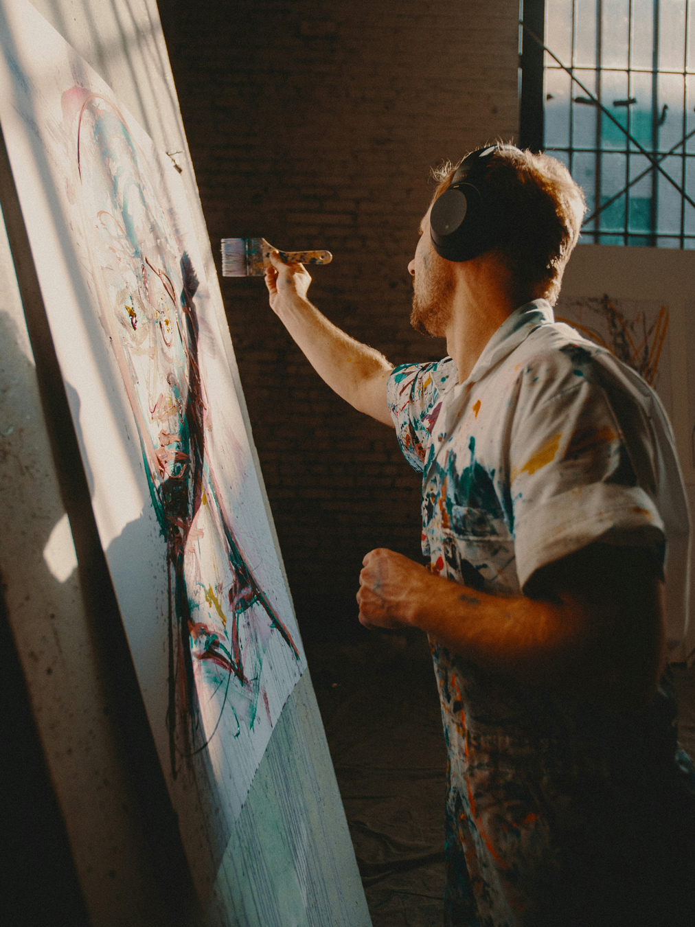 male painter using wide brush to create a portrait