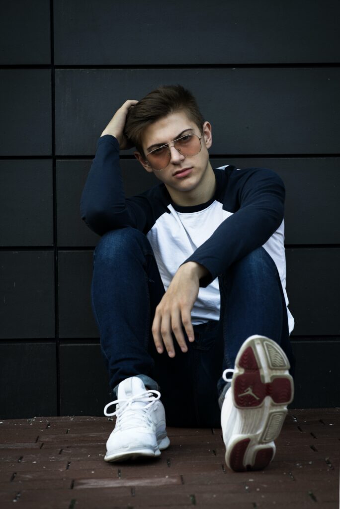 man posed sitting on ground with elbows resting on knees