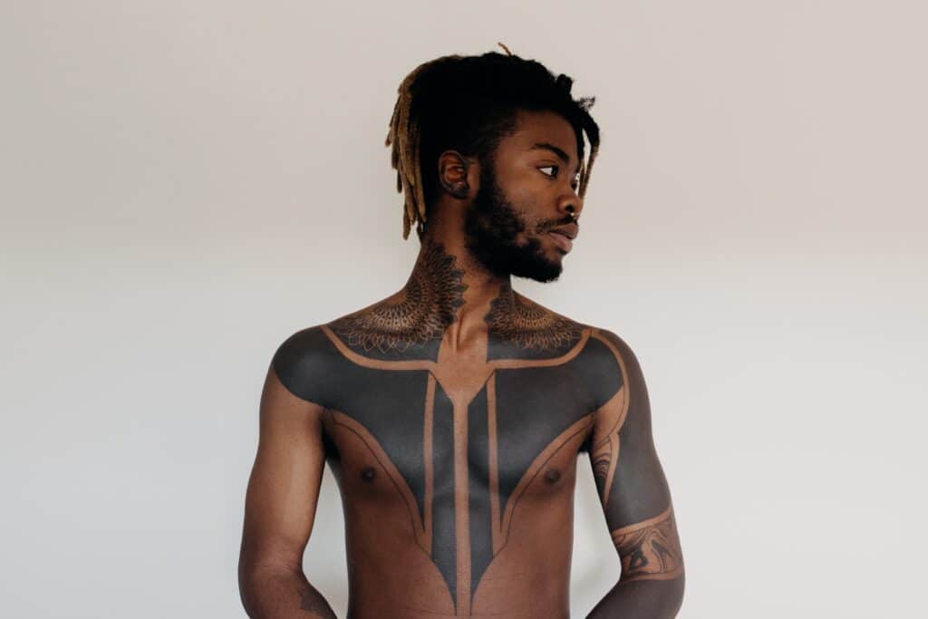 man with abstract symmetrical tattoo design on his neck and chest