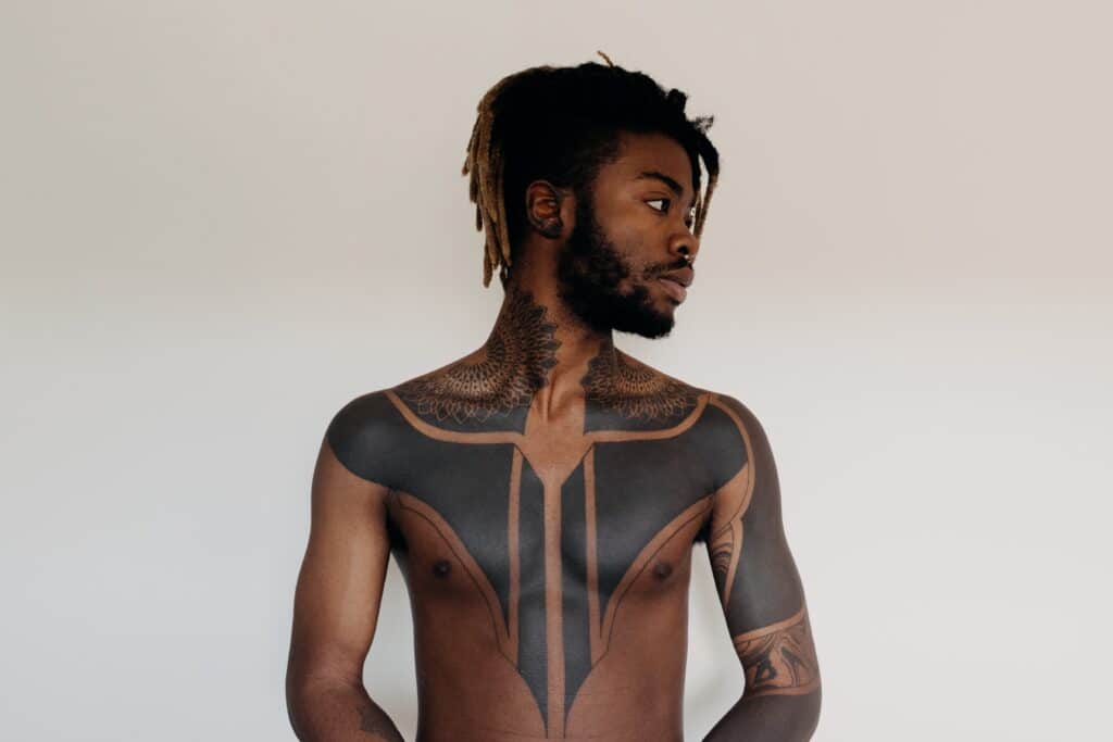 homme avec un tatouage abstrait et symétrique sur le cou et la poitrine