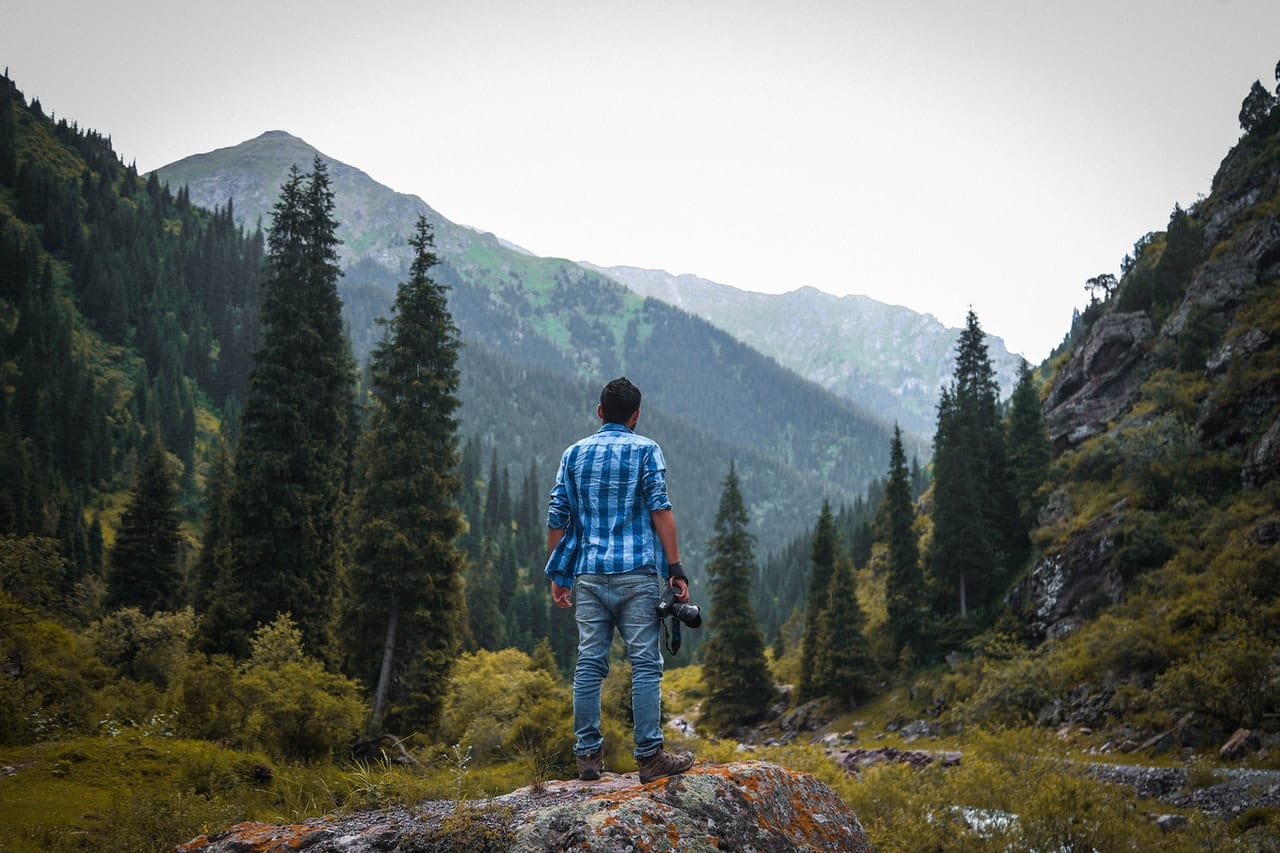 homme tenant un appareil photo en montagne