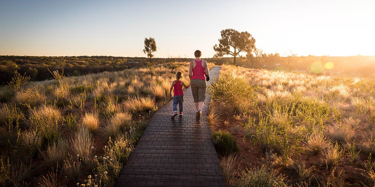 mãe e filho passeando em um caminho natural ao pôr do sol