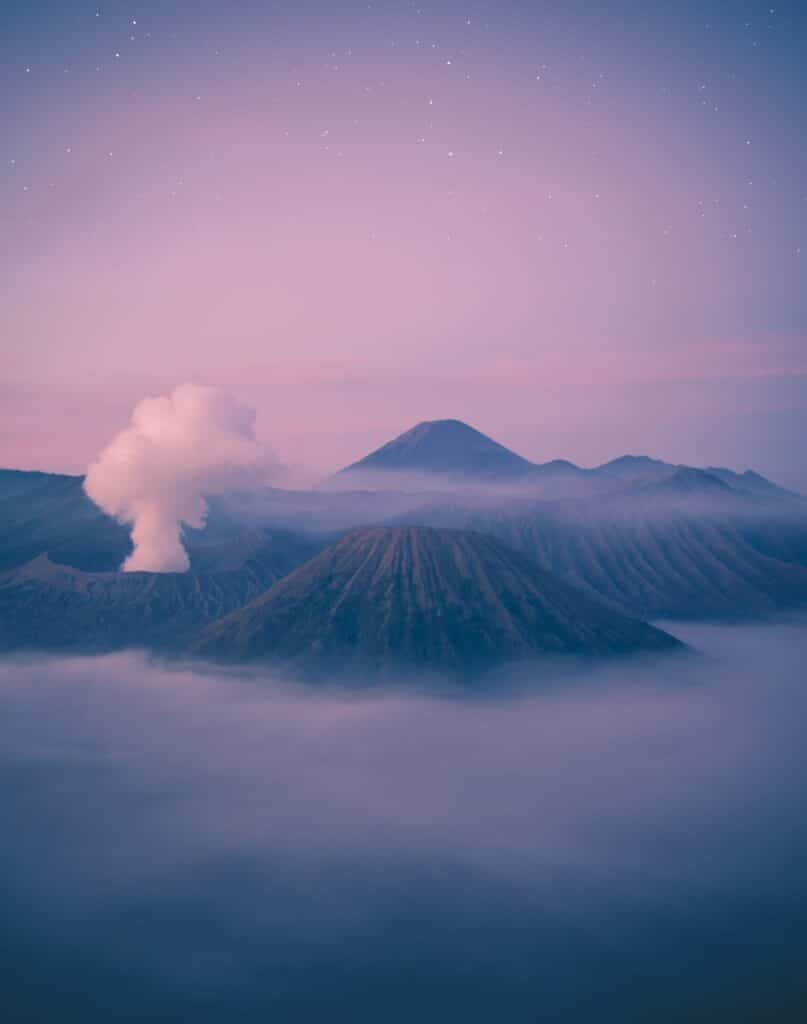 montañas y volcán humeante en la bruma matinal