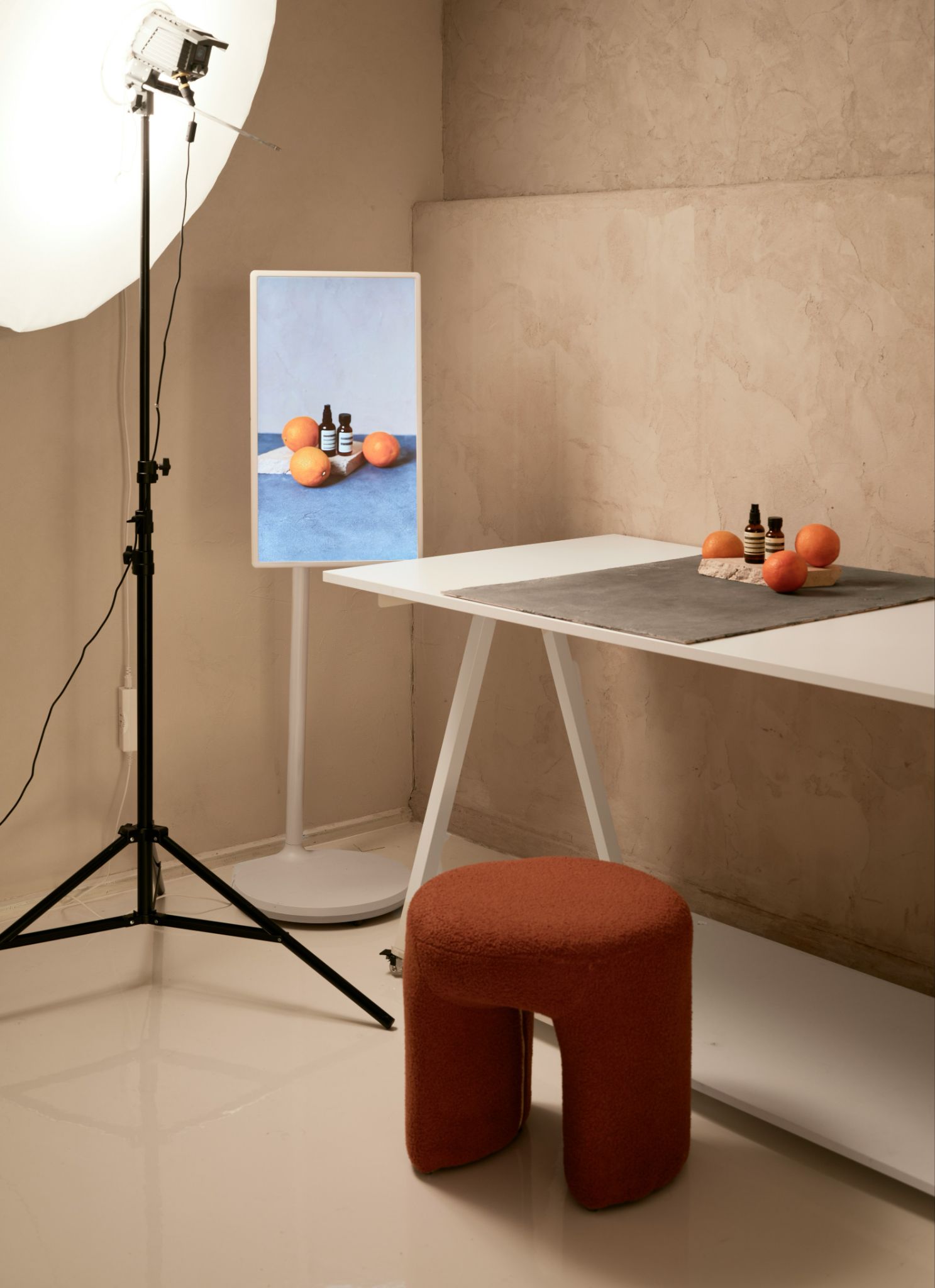 Minimal studio setup with oranges, bottles, and softbox lighting