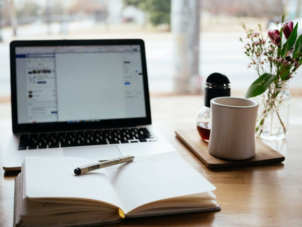 notepad and pen for planning in front of a laptop and coffee cup