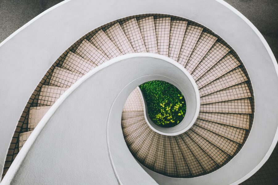 overhead shot of white and brown concrete spiral stairs with green plants in center scaled e1714424127834
