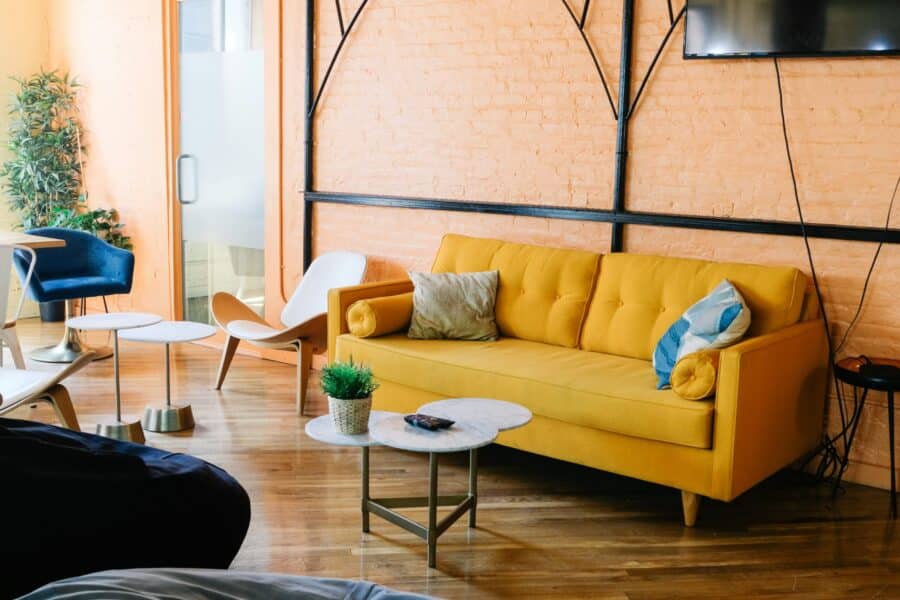 pantone apricot walls with yellow couch and modern white side tables scaled e1709680692403