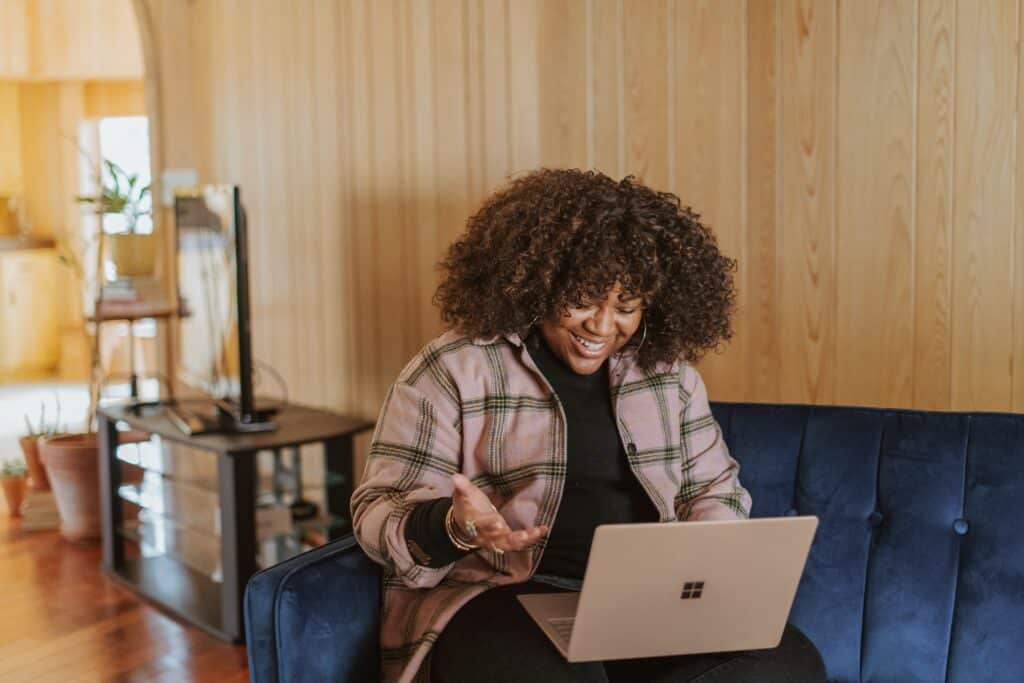 person sitting on couch holding a laptop and smiling