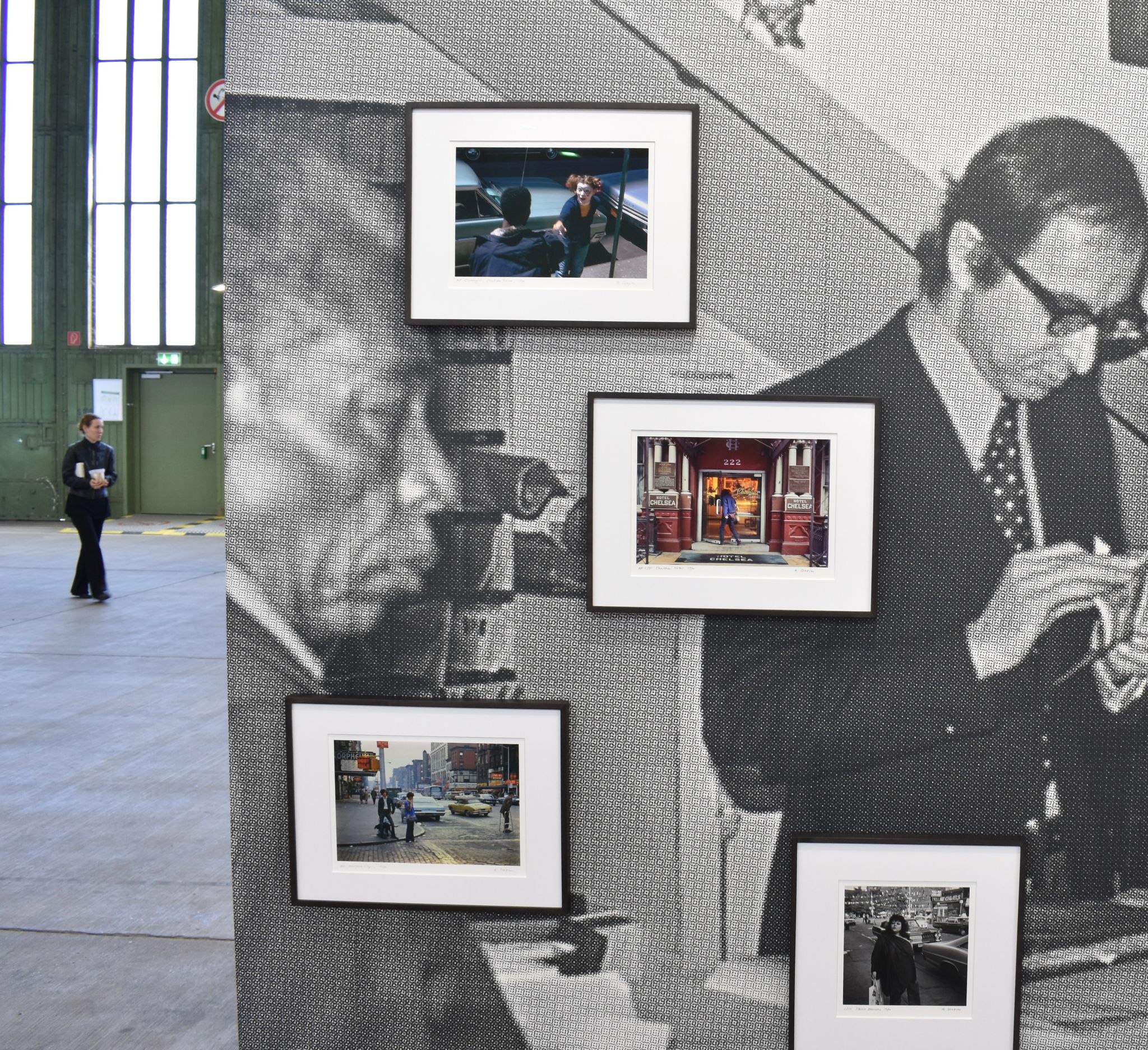 Framed New York street photographs displayed on a gallery wall beside a large black-and-white portrait.