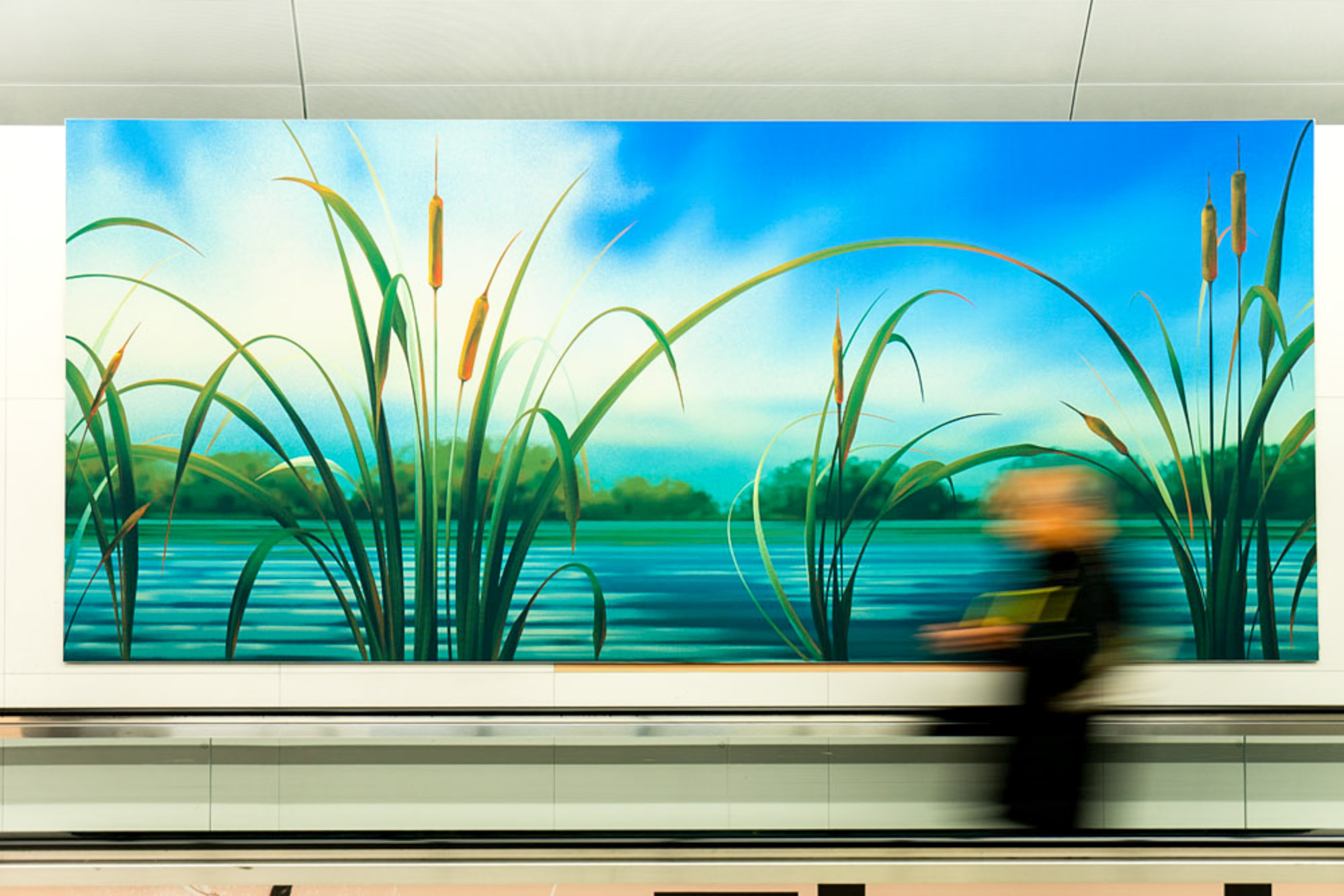 Colorful mural of reeds beside a lake, viewed as a commuter walks past.