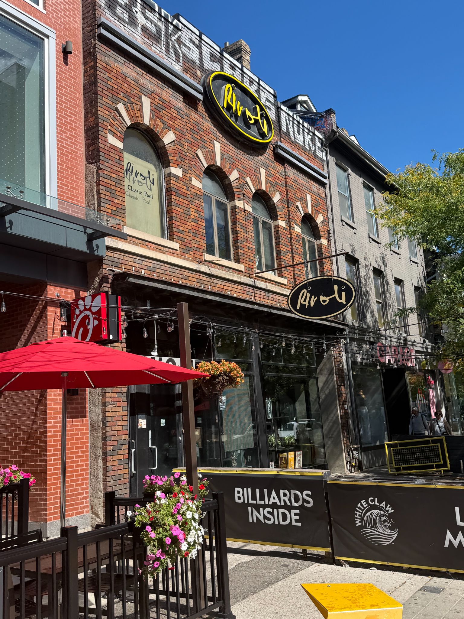 Rivoli pool hall storefront with historic brick arches, patio seating, and a billiards sign