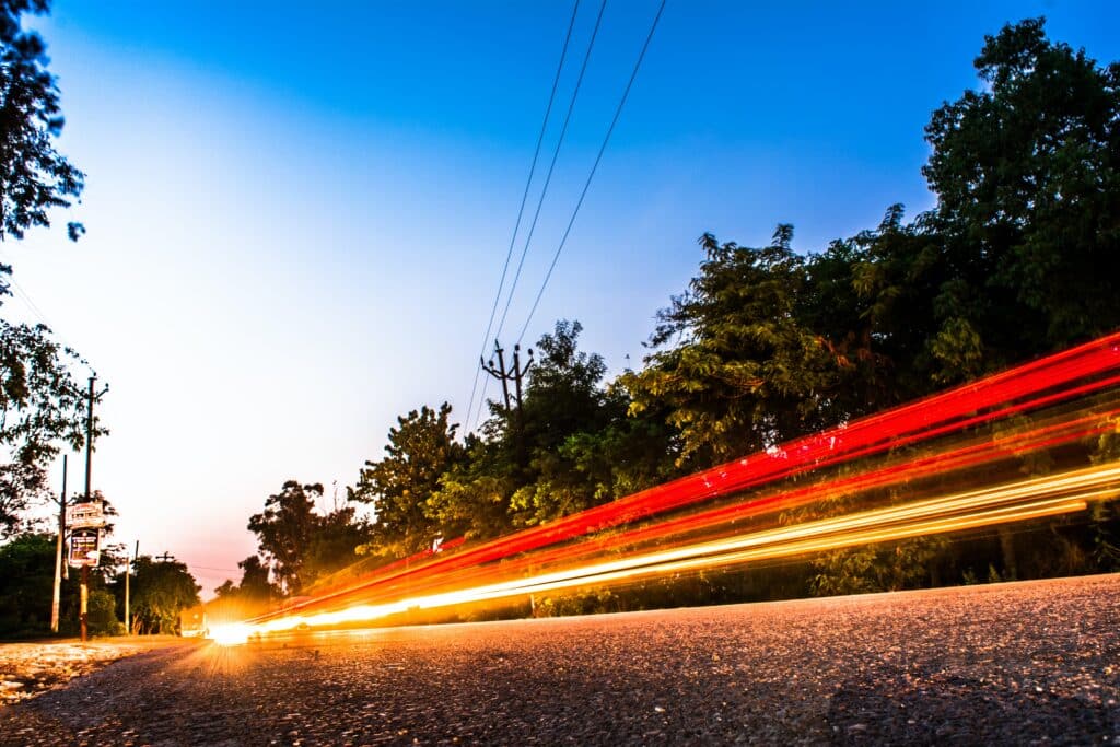 estrada e árvores com linhas vermelhas e amarelas dos faróis dos carros, fotografadas com baixa velocidade do obturador