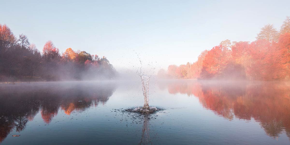 rocha espirrando em um lago com neblina ao fundo