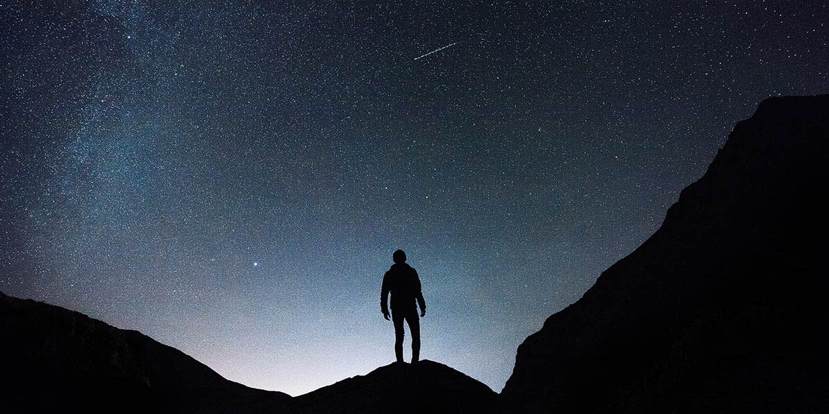 silhueta de um homem com o céu estrelado