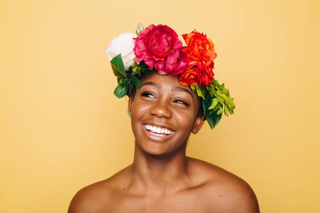 femme noire souriante portant une couronne de fleurs