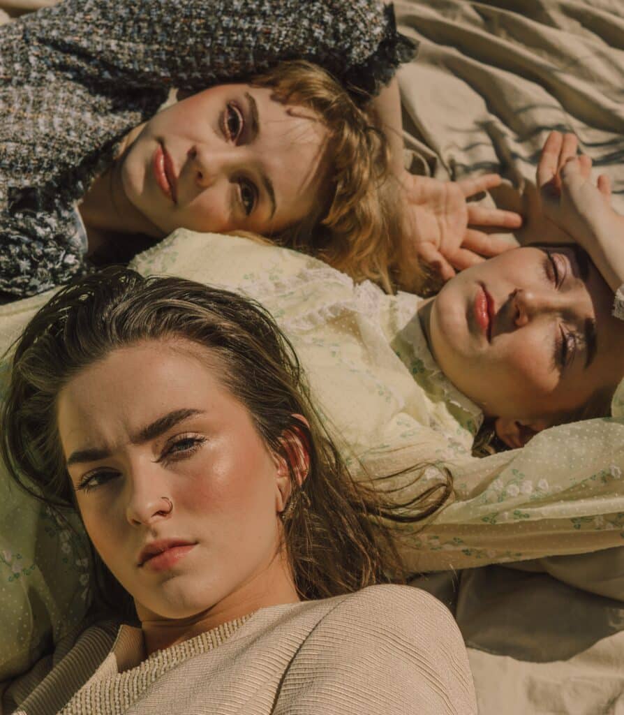 three women wearing dresses lying on neutral fabric