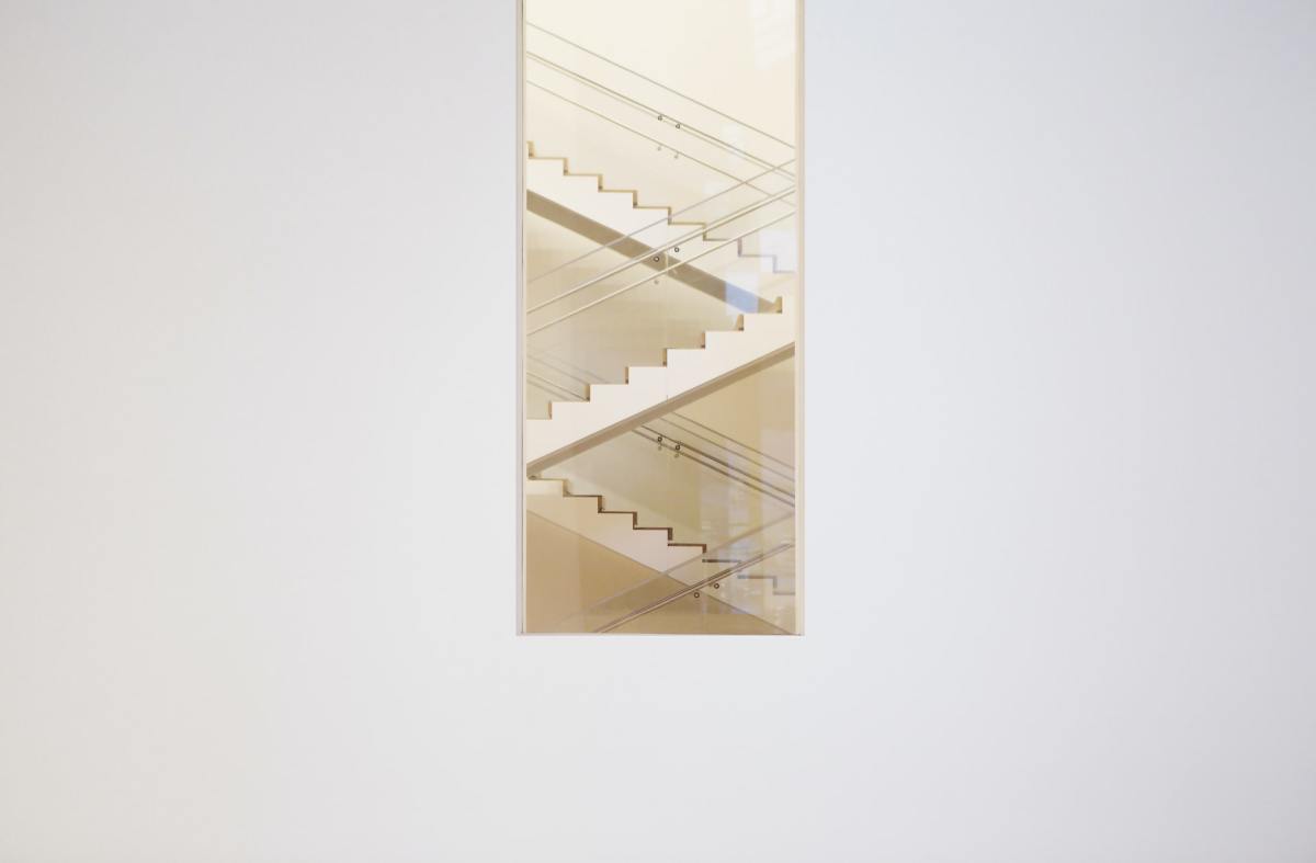 Photo minimaliste d'un escalier à travers la fenêtre d'un bâtiment blanc