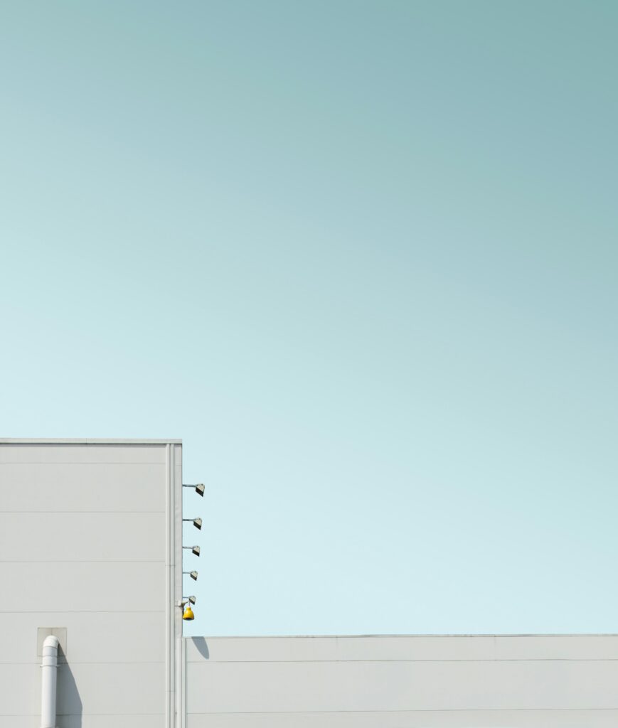 Topo de um edifício branco moderno com luzes de arandela amarelas contra um céu azul claro