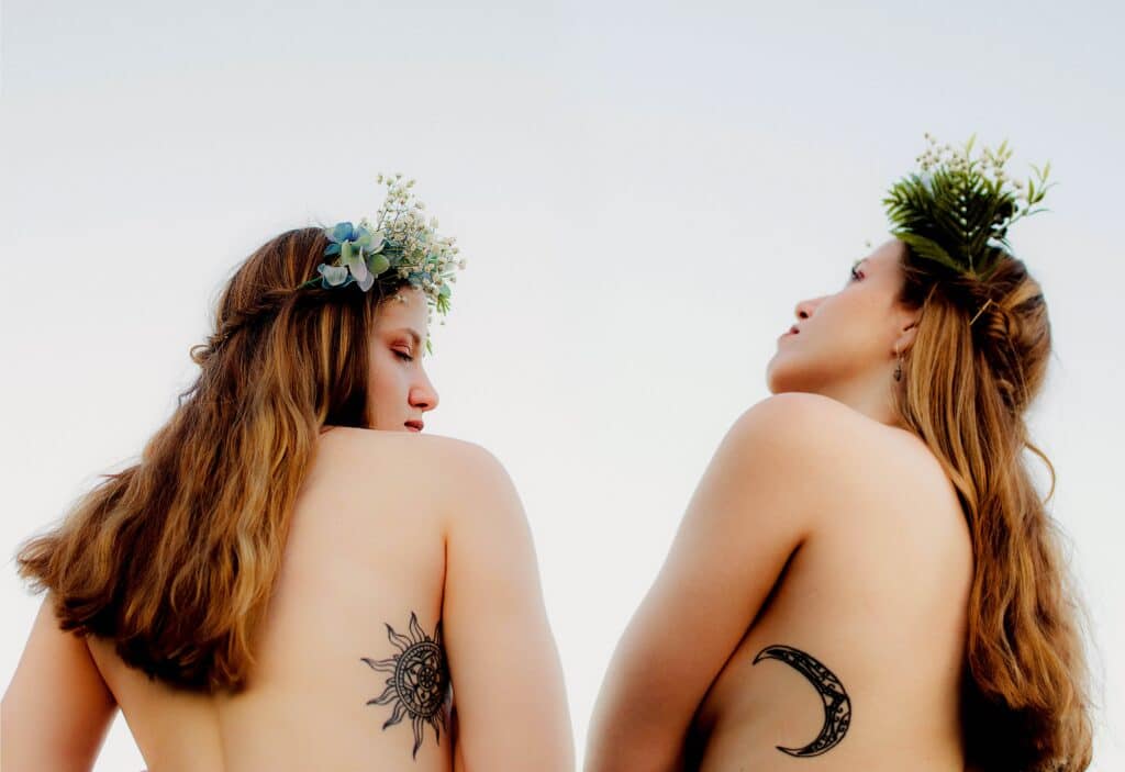 duas mulheres usando coroas de flores com uma tatuagem de sol e lua