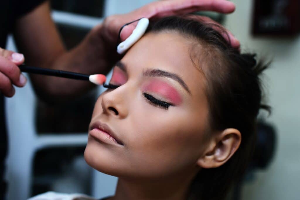 femme appliquant un fard à paupières rose sous un éclairage uniforme