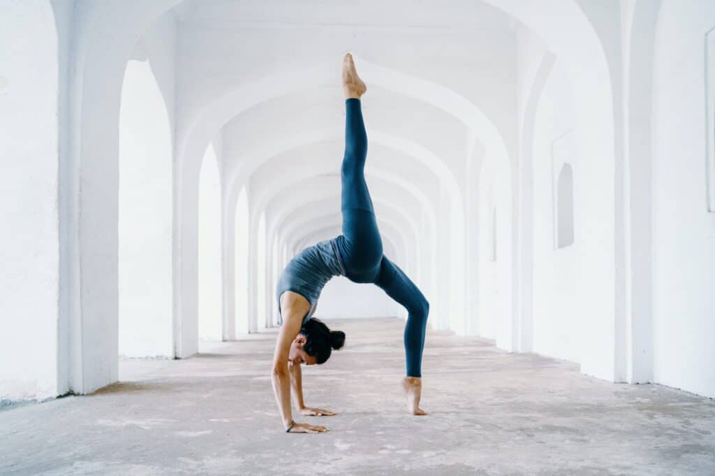 woman doing backbend pose under white arches