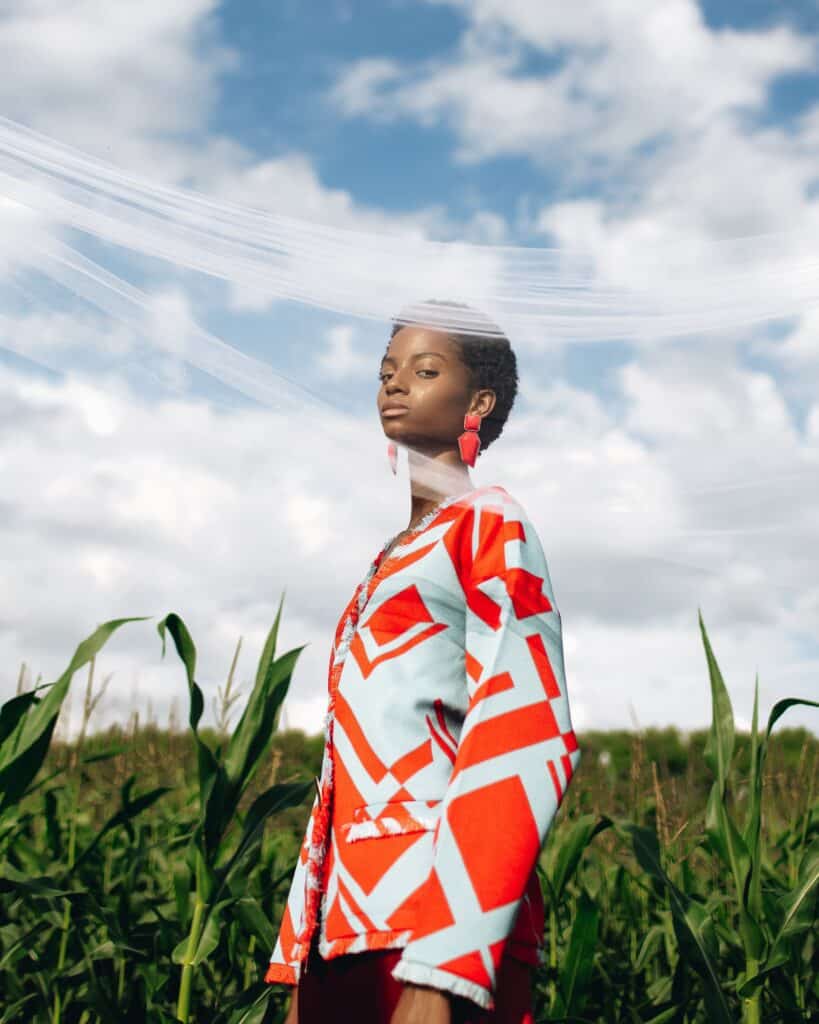 woman in bold patterned jacket standing in a field of young corn