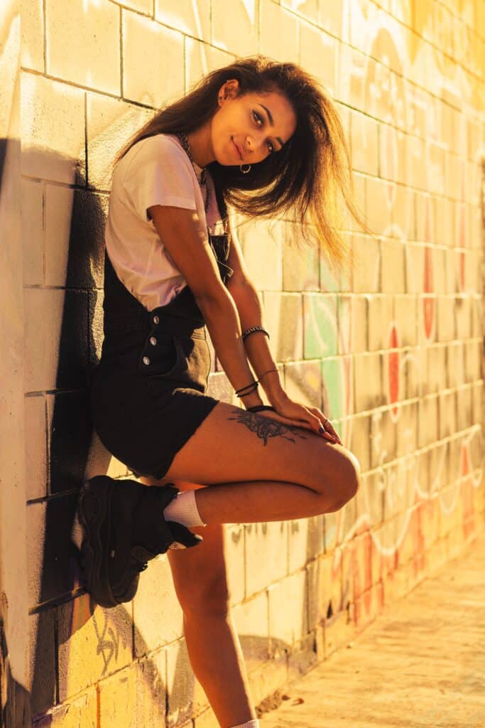 woman leaning against brick wall one knee bent