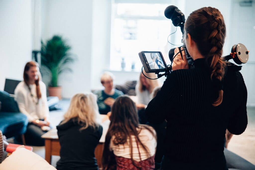 woman shooting video of a group of people seated around a table